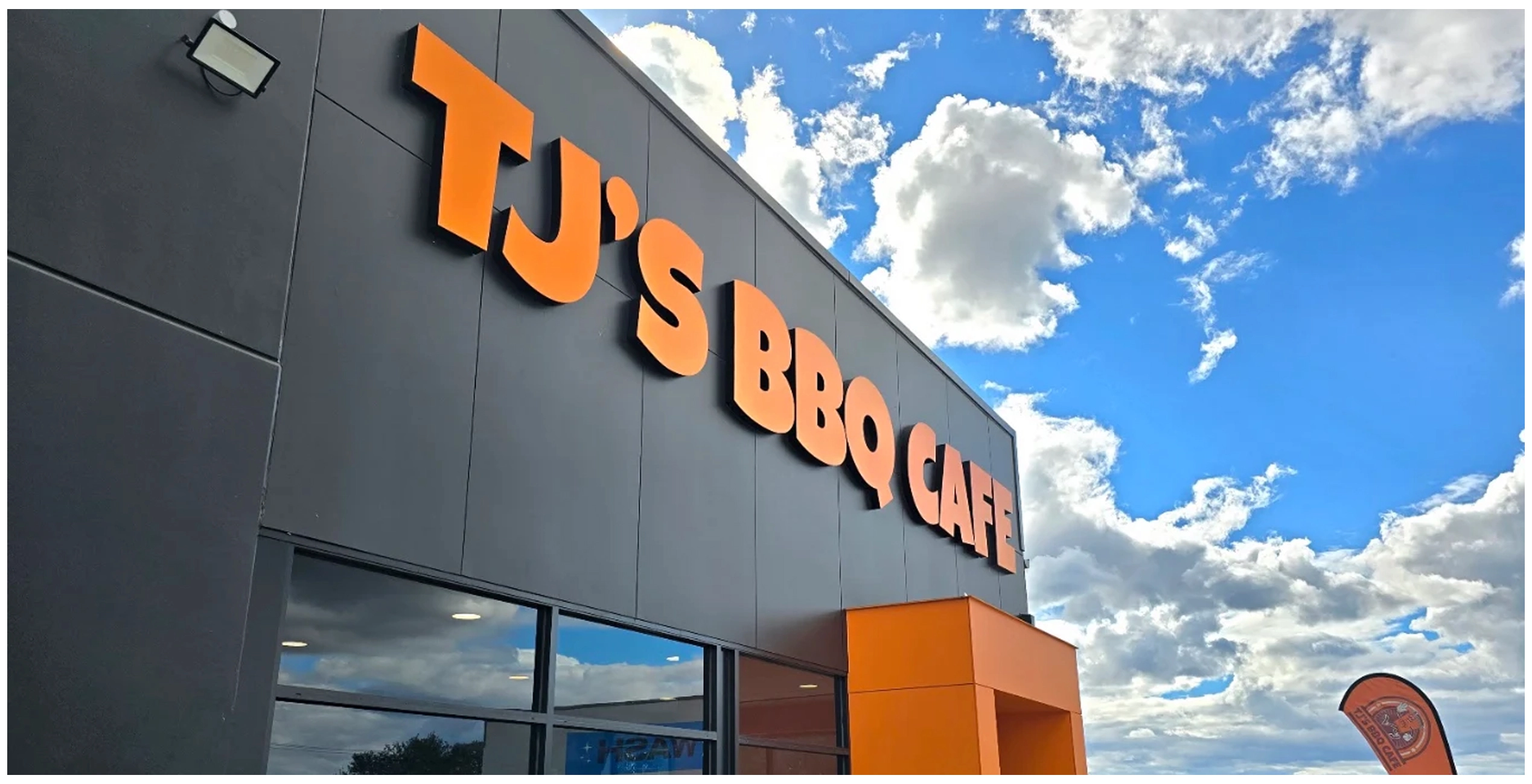 Close-up of the TJ's BBQ Cafe storefront signage lettering against a blue sky